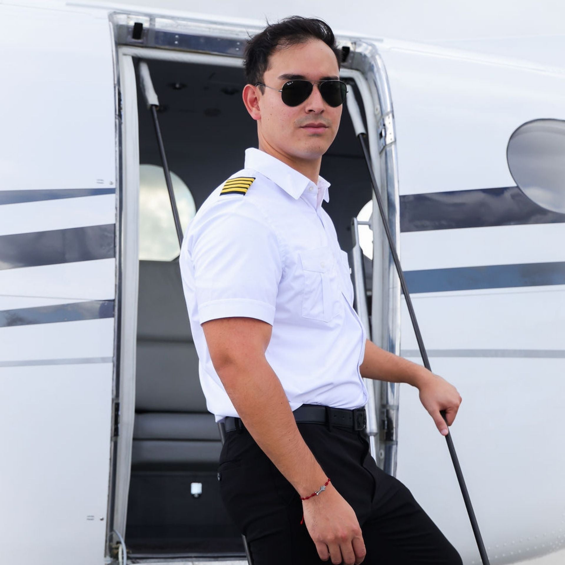 person standing on airplane stairs, wearing sunglasses and Skyshield's Men's Signature Short Sleeve pilot uniform shirt with black pants